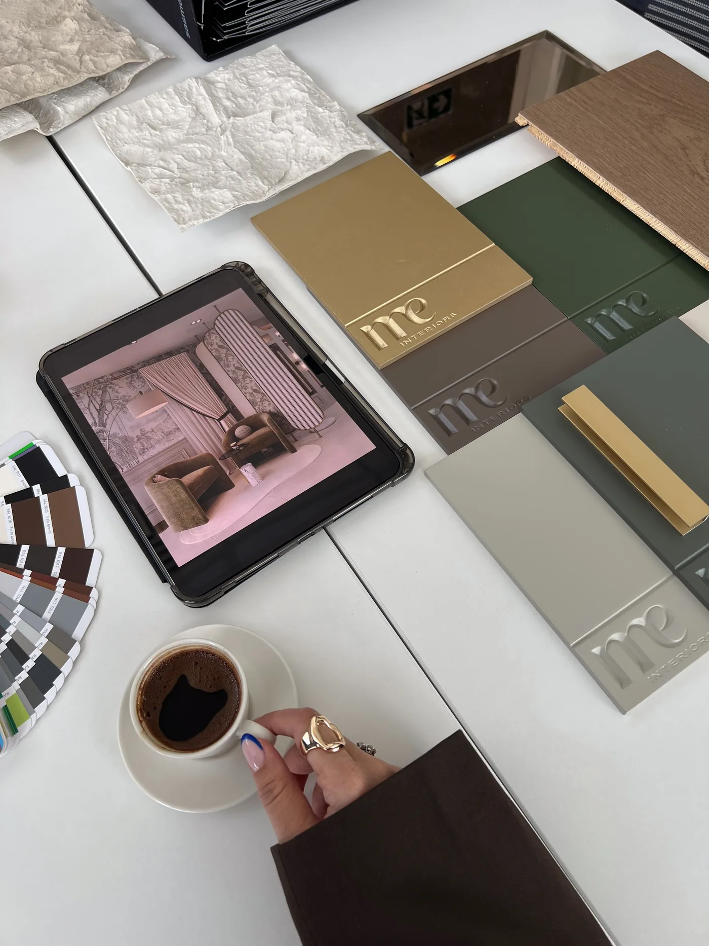 ME Interiors çalışma masası — logolu malzeme numuneleri, renk kartelası ve tablette render